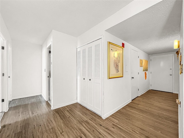 hall with wood-type flooring and a textured ceiling