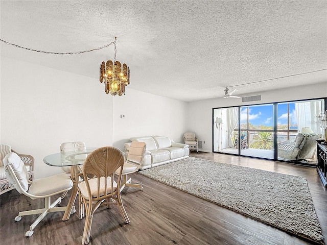 dining room featuring ceiling fan with notable chandelier, dark hardwood / wood-style floors, and a textured ceiling