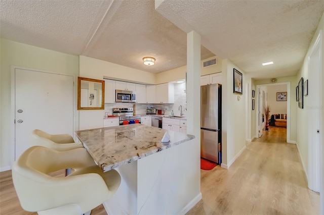 kitchen featuring white cabinets, appliances with stainless steel finishes, a textured ceiling, and sink