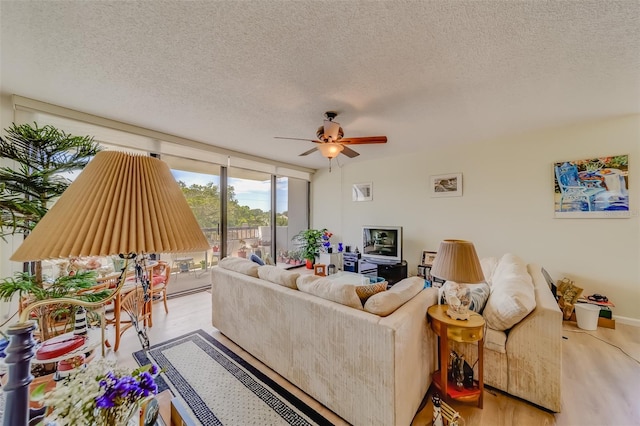 living room featuring floor to ceiling windows, ceiling fan, a textured ceiling, and light wood-type flooring