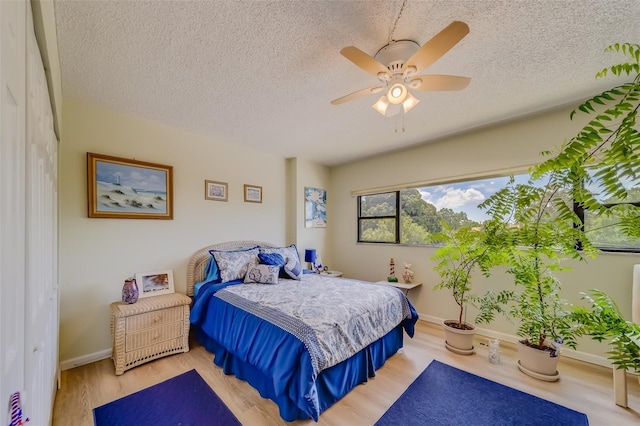 bedroom featuring ceiling fan, a closet, a textured ceiling, and light hardwood / wood-style flooring