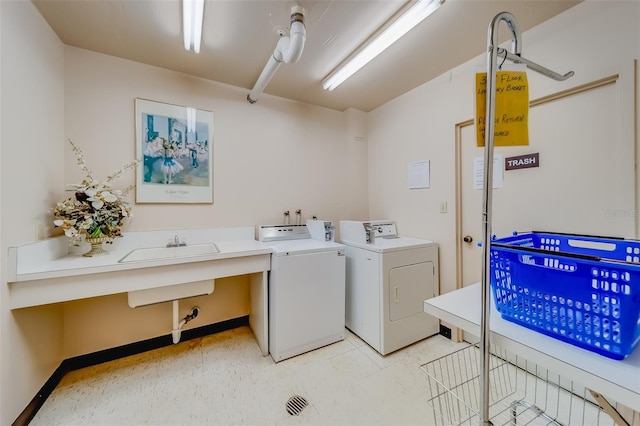 clothes washing area with separate washer and dryer and sink