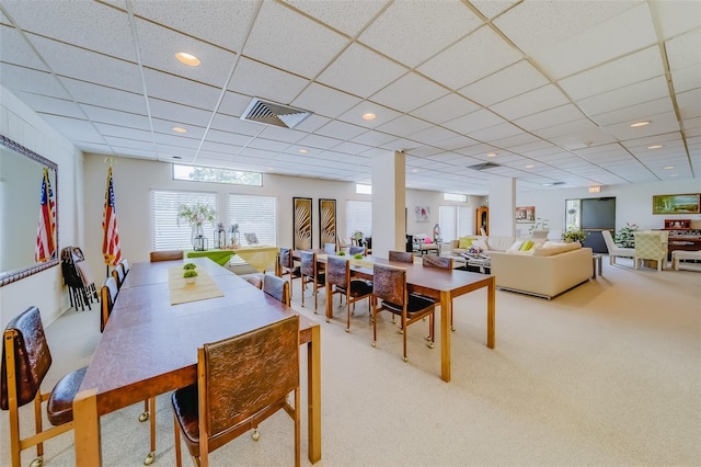 carpeted dining area with a drop ceiling