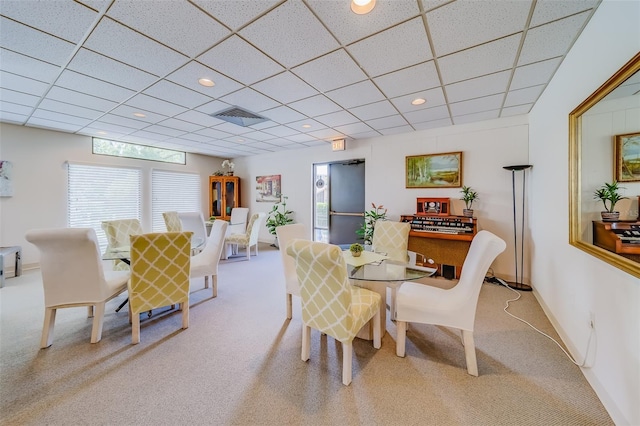 dining area featuring light colored carpet and a drop ceiling