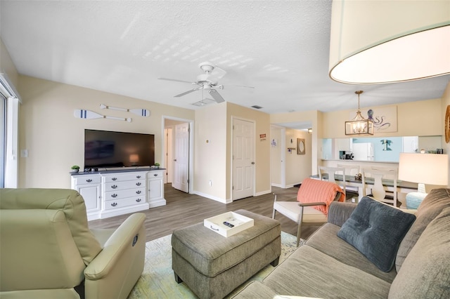 living room featuring ceiling fan with notable chandelier, a textured ceiling, and hardwood / wood-style flooring