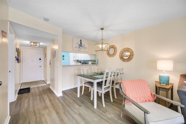 dining area featuring light hardwood / wood-style flooring, a chandelier, and a textured ceiling