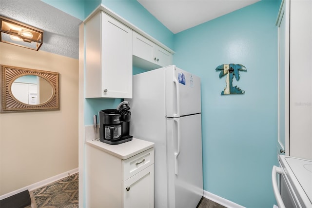 kitchen featuring range, a textured ceiling, white fridge, and white cabinetry