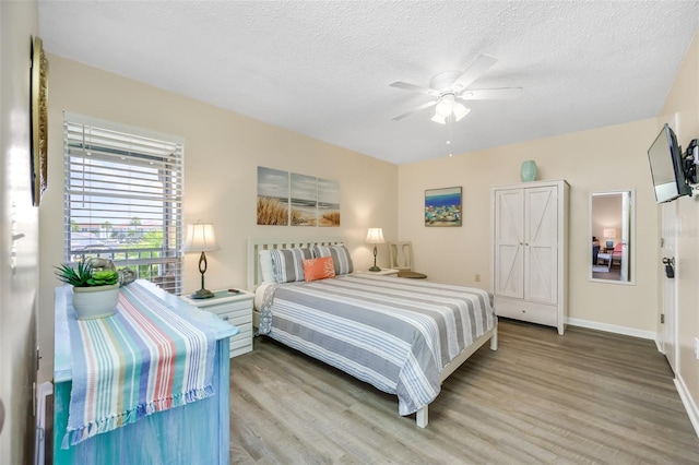 bedroom with a textured ceiling, light hardwood / wood-style floors, and ceiling fan