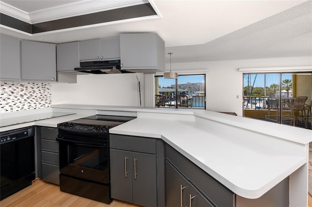 kitchen featuring pendant lighting, black appliances, kitchen peninsula, and exhaust hood