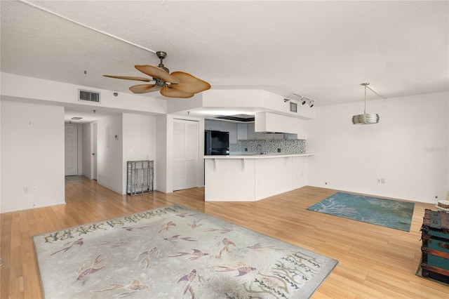 unfurnished living room featuring a textured ceiling, ceiling fan, and light wood-type flooring