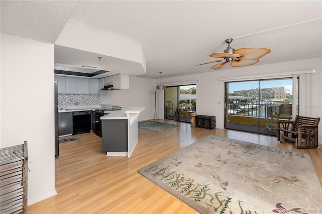 kitchen with kitchen peninsula, ceiling fan, decorative backsplash, light wood-type flooring, and a textured ceiling