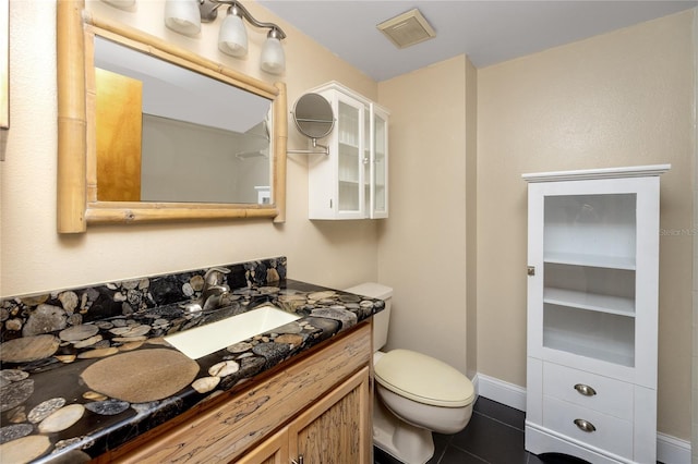 bathroom with toilet, vanity, and tile patterned flooring