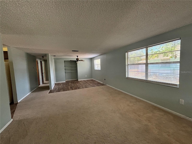 carpeted empty room featuring a textured ceiling, plenty of natural light, and ceiling fan