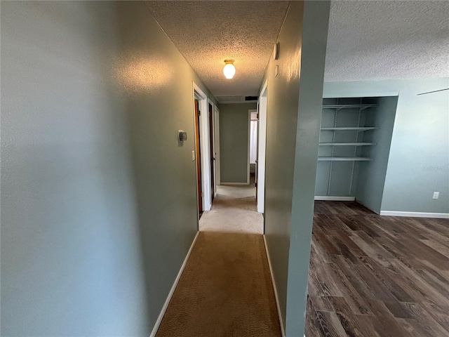 hallway with a textured ceiling and dark hardwood / wood-style floors