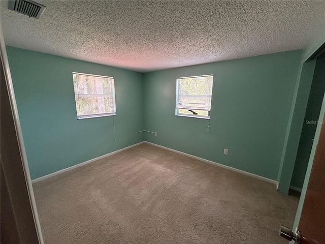 carpeted empty room with a textured ceiling