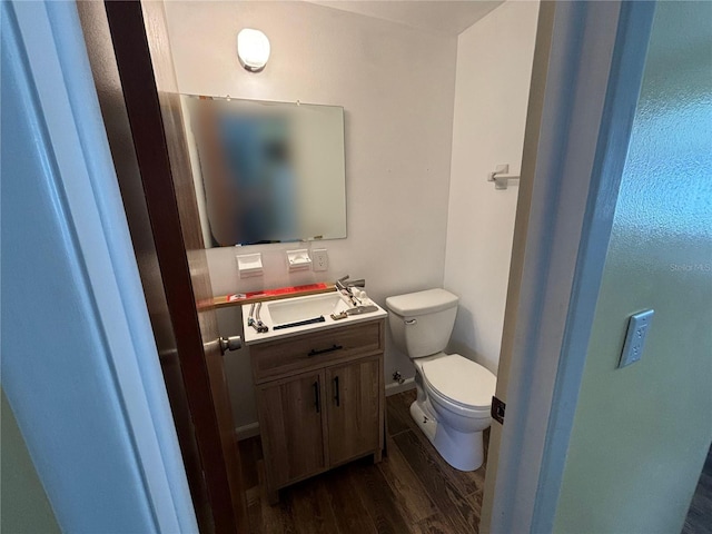 bathroom with toilet, vanity, and hardwood / wood-style flooring