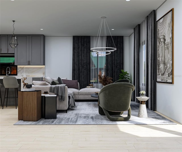 living room with light hardwood / wood-style floors, sink, and an inviting chandelier