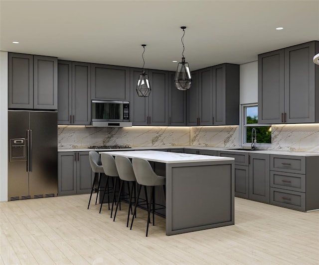 kitchen with gray cabinetry, a center island, pendant lighting, light hardwood / wood-style floors, and appliances with stainless steel finishes