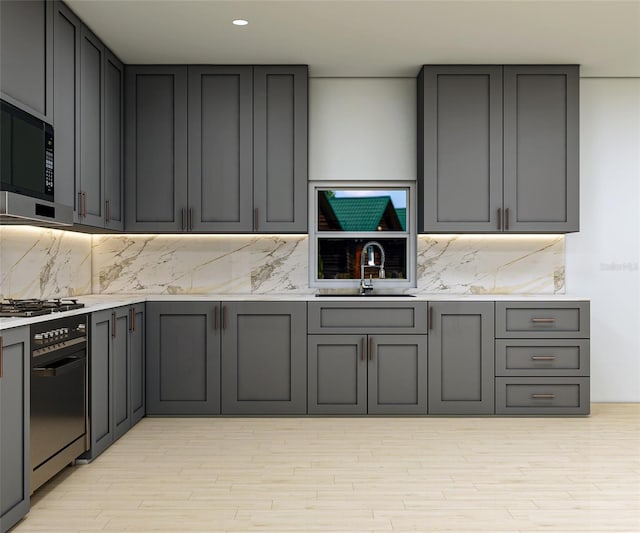 kitchen featuring decorative backsplash, gray cabinets, sink, and appliances with stainless steel finishes