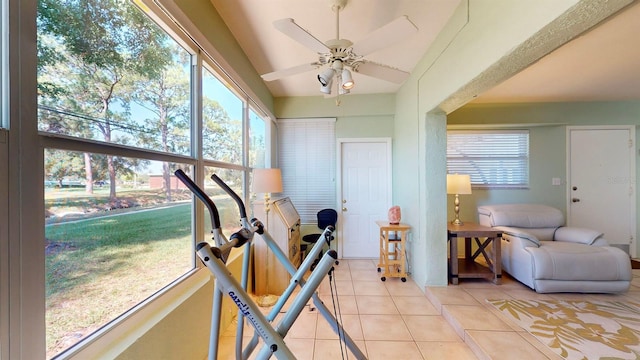 workout area featuring ceiling fan, light tile patterned flooring, and a healthy amount of sunlight