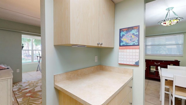 kitchen with light brown cabinets, light tile patterned flooring, and hanging light fixtures