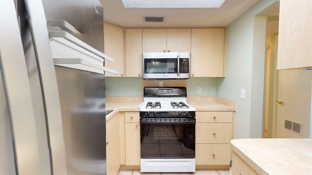 kitchen with light brown cabinets, white gas range, and light tile patterned floors