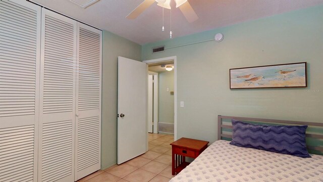 tiled bedroom with ceiling fan and a closet