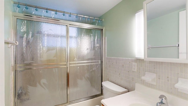 full bathroom with toilet, combined bath / shower with glass door, tile walls, and vanity