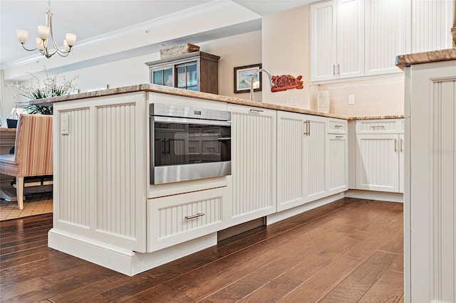 kitchen with ornamental molding, backsplash, a notable chandelier, and stainless steel oven