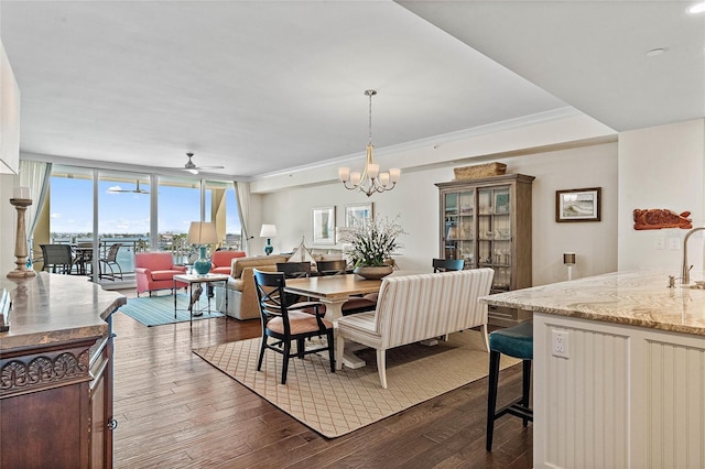 dining area featuring ceiling fan with notable chandelier, crown molding, sink, a wall of windows, and dark hardwood / wood-style floors