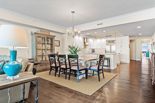 dining area featuring sink, a notable chandelier, dark hardwood / wood-style flooring, and crown molding