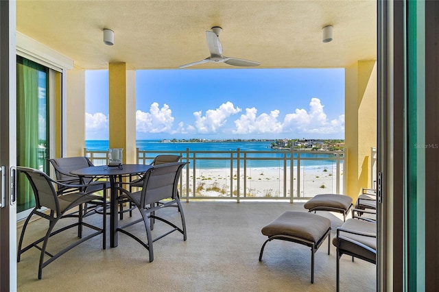 balcony with ceiling fan, a water view, and a view of the beach