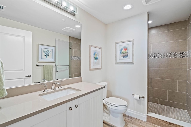 bathroom featuring toilet, vanity, and tiled shower