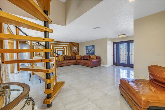 stairway featuring french doors, wood walls, and a textured ceiling