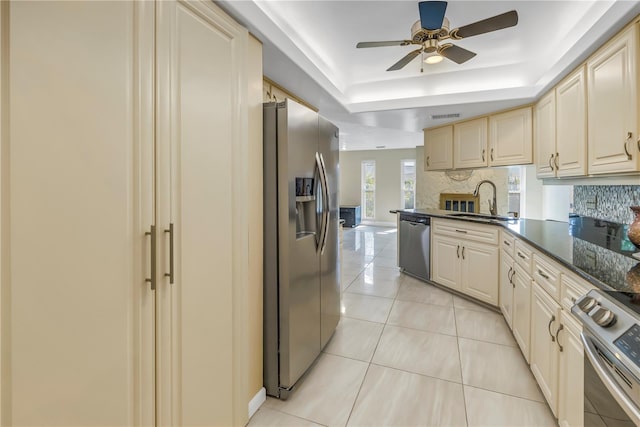 kitchen with appliances with stainless steel finishes, decorative backsplash, sink, light tile patterned floors, and a tray ceiling