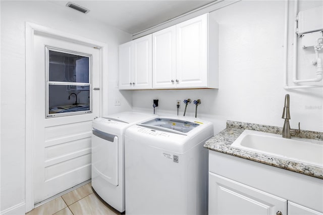 clothes washing area featuring cabinets, sink, light tile patterned flooring, and washing machine and clothes dryer