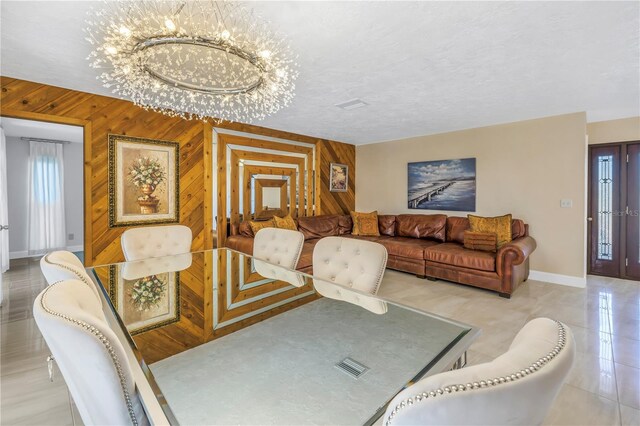 dining room featuring a notable chandelier, wooden walls, and a textured ceiling