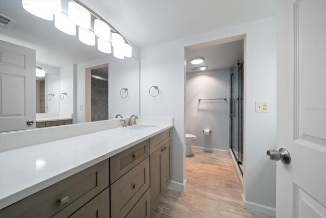 bathroom featuring vanity, a shower with shower door, and toilet