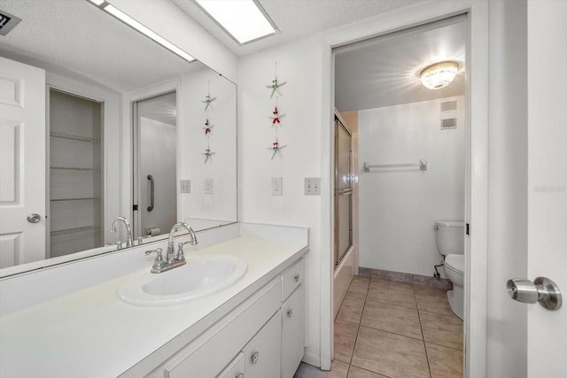 full bathroom featuring tile patterned floors, vanity, enclosed tub / shower combo, and toilet