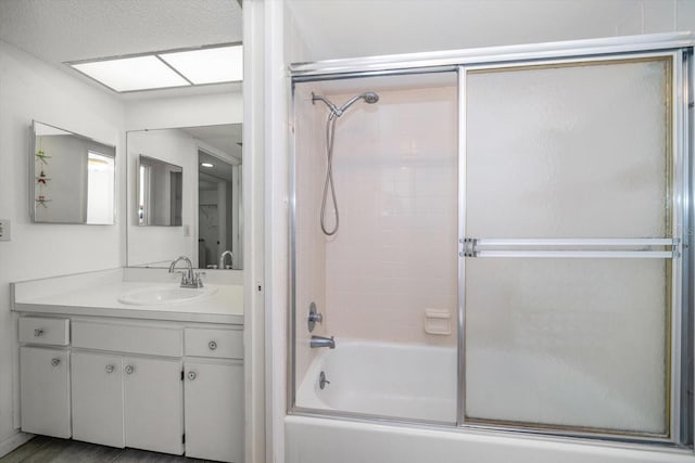 bathroom with a textured ceiling, vanity, and enclosed tub / shower combo