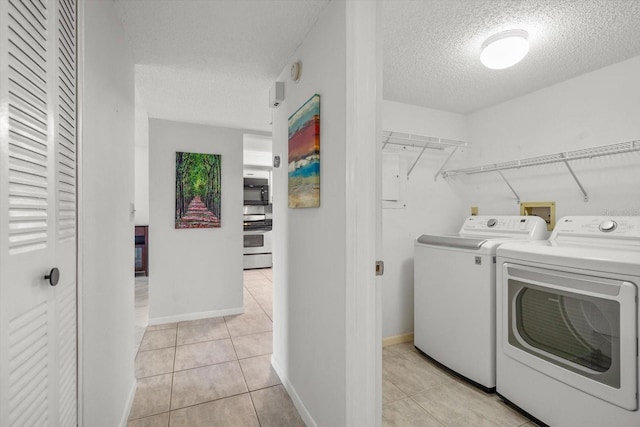 laundry room featuring washer and dryer, light tile patterned flooring, and a textured ceiling