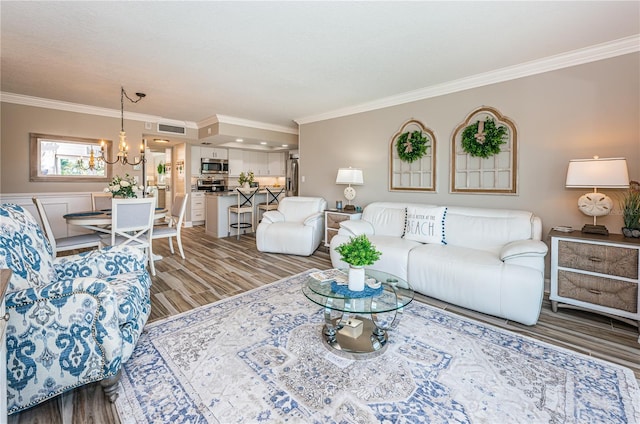 living room with a chandelier, wood-type flooring, and ornamental molding