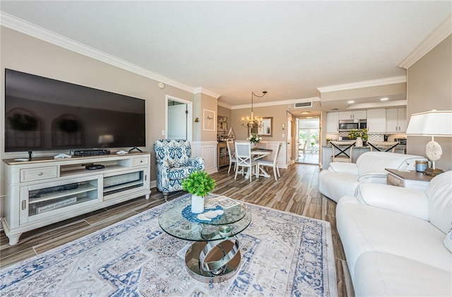 living room featuring hardwood / wood-style floors, crown molding, and a chandelier