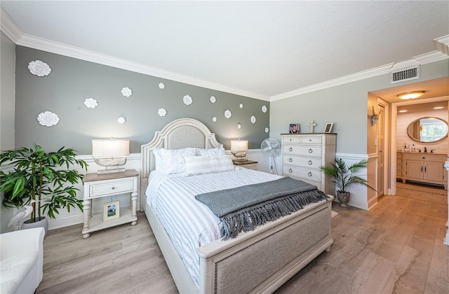 bedroom with light wood-type flooring, ornamental molding, and connected bathroom