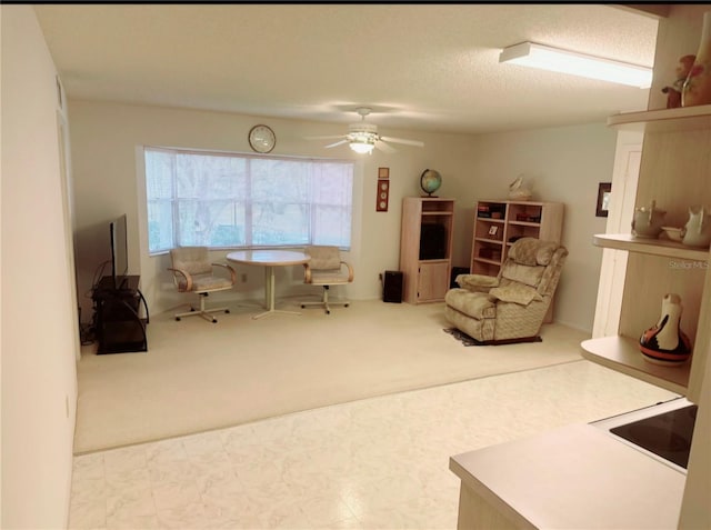 living area featuring ceiling fan, light colored carpet, and a textured ceiling