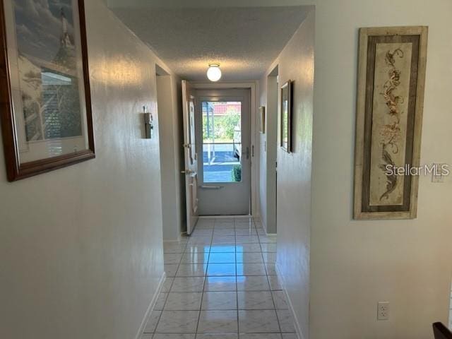 corridor featuring light tile patterned floors and a textured ceiling