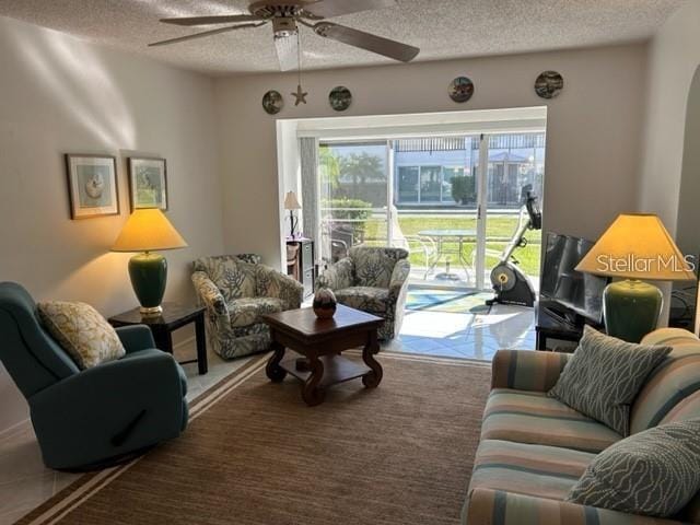 living room with ceiling fan and a textured ceiling