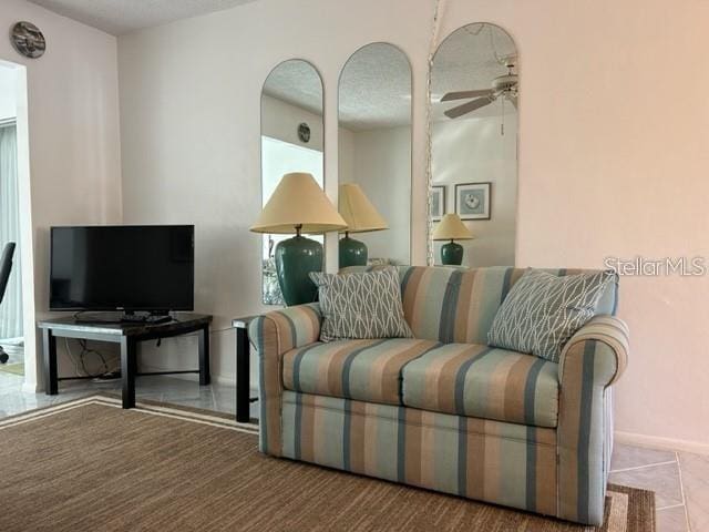 sitting room featuring a textured ceiling, tile patterned floors, and ceiling fan