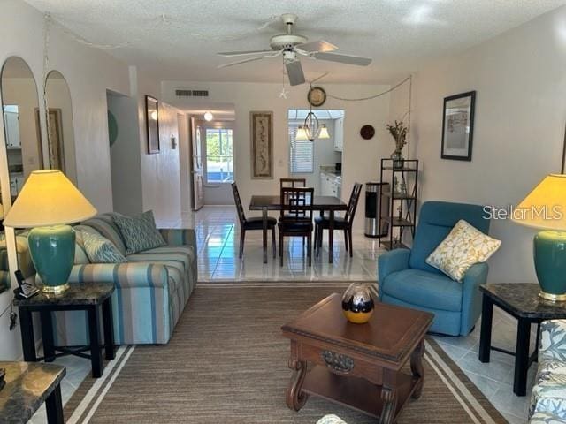 living room featuring tile patterned floors, ceiling fan, and a textured ceiling