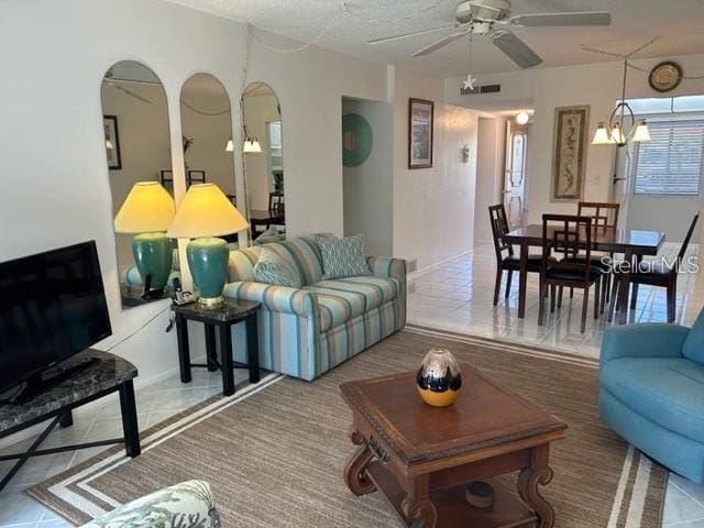 tiled living room featuring ceiling fan with notable chandelier